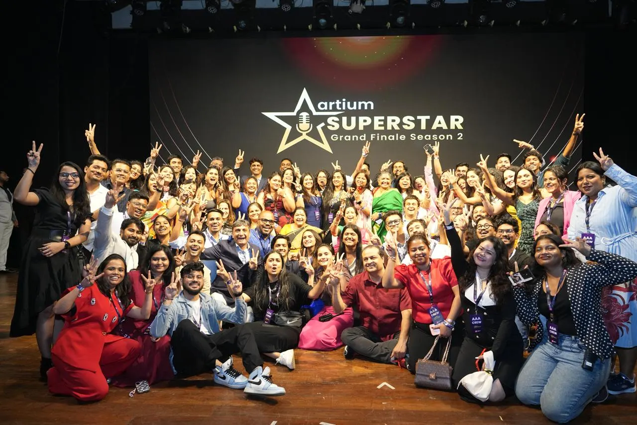 The Artium team together on stage, smiling and making victory signs
