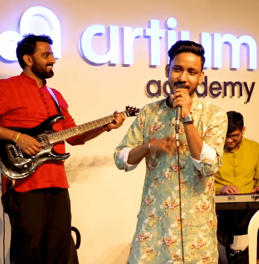 Two Artium teammates singing and playing guitar at an office jam session