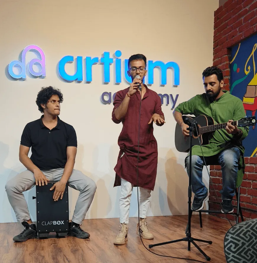 Artium teammates playing cajón, singing and playing guitar in front of the Artium sign