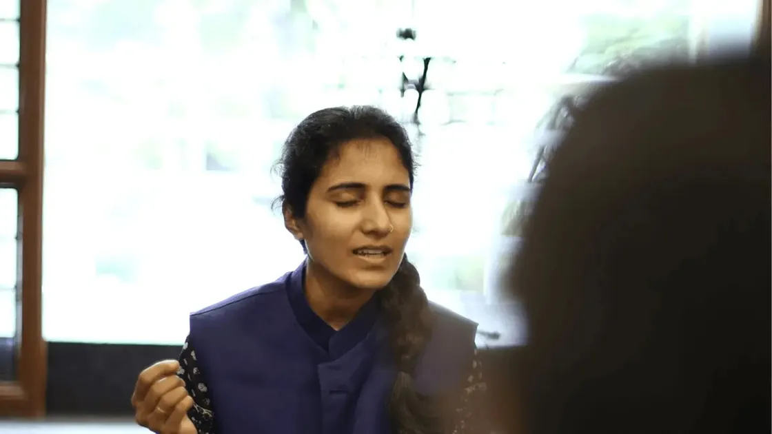 A teacher singing with her eyes closed during a group vocal session