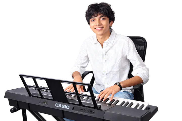 A teenage student smiling at a keyboard