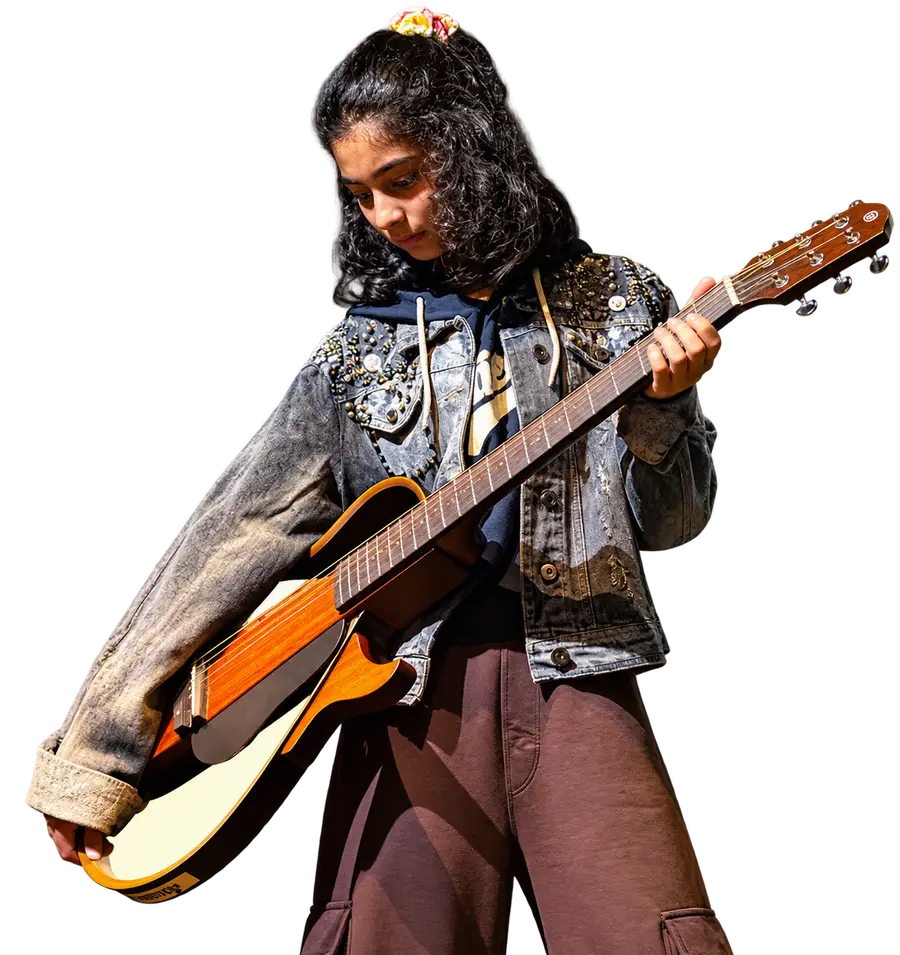 An Artium learner playing an acoustic guitar